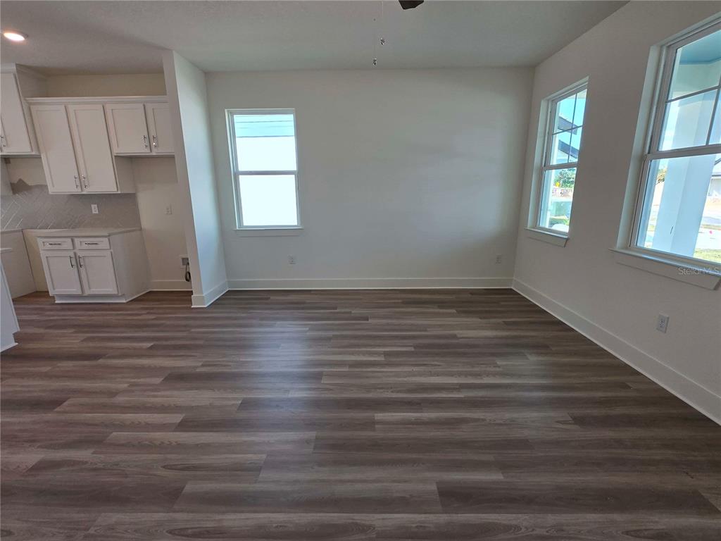 An empty room with wood-look flooring, white walls, and white kitchen cabinets — 3836 DAYBREAK RUN LOOP, SPRING HILL, FL