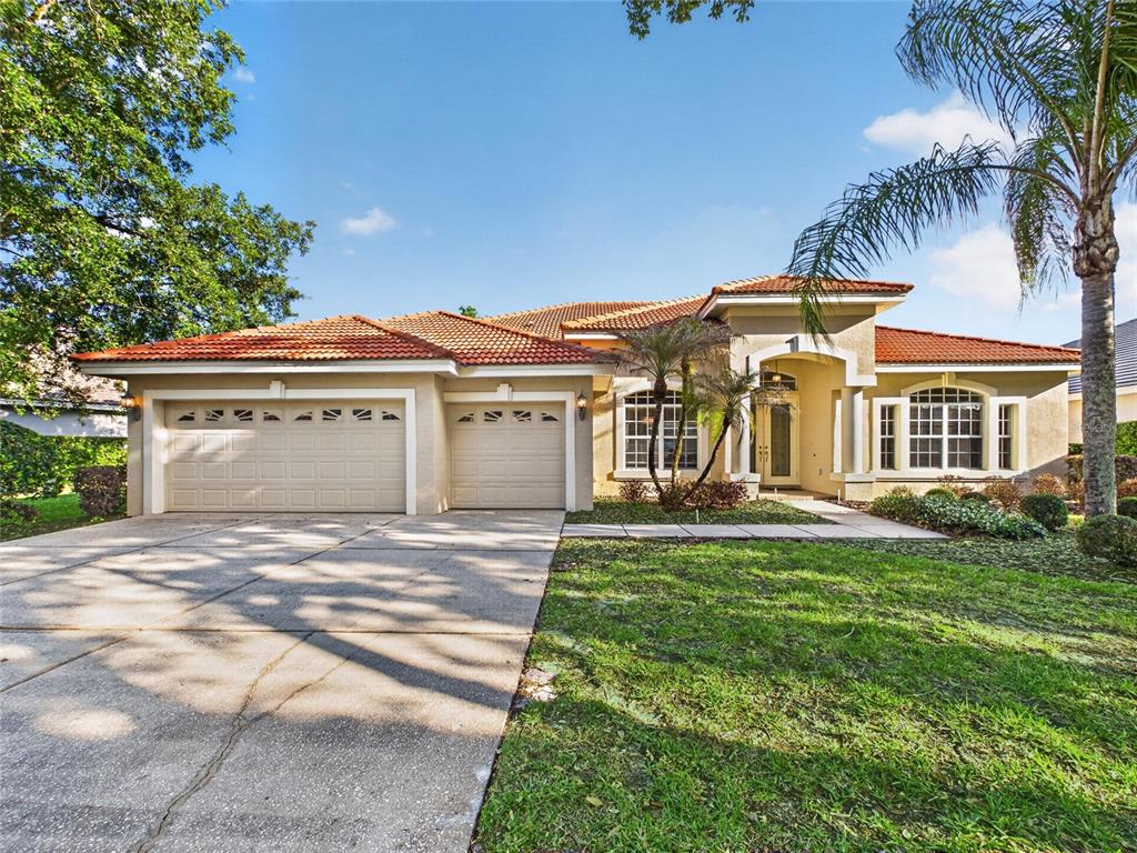 A single-story house with a tile roof, two-car garage, and a large tree in front — 10207 ESTUARY DRIVE, TAMPA, FL