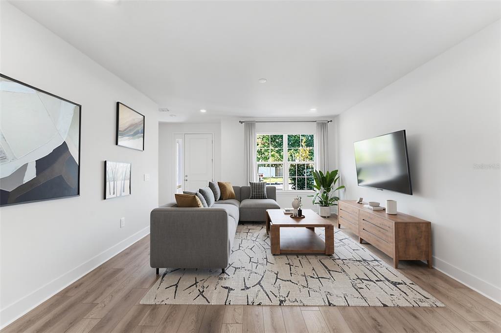 A living room features a gray sectional sofa, a wooden coffee table, and a wall-mounted television — 2321 HUANIER COURT, APOPKA, FL