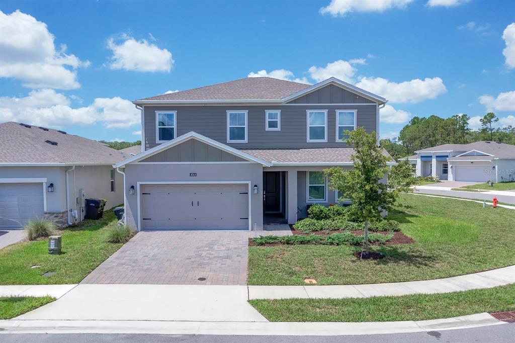 A two-story suburban house with a gray exterior, a two-car garage, and a paved driveway — 4064 REDBRIDGE LOOP, DAVENPORT, FL