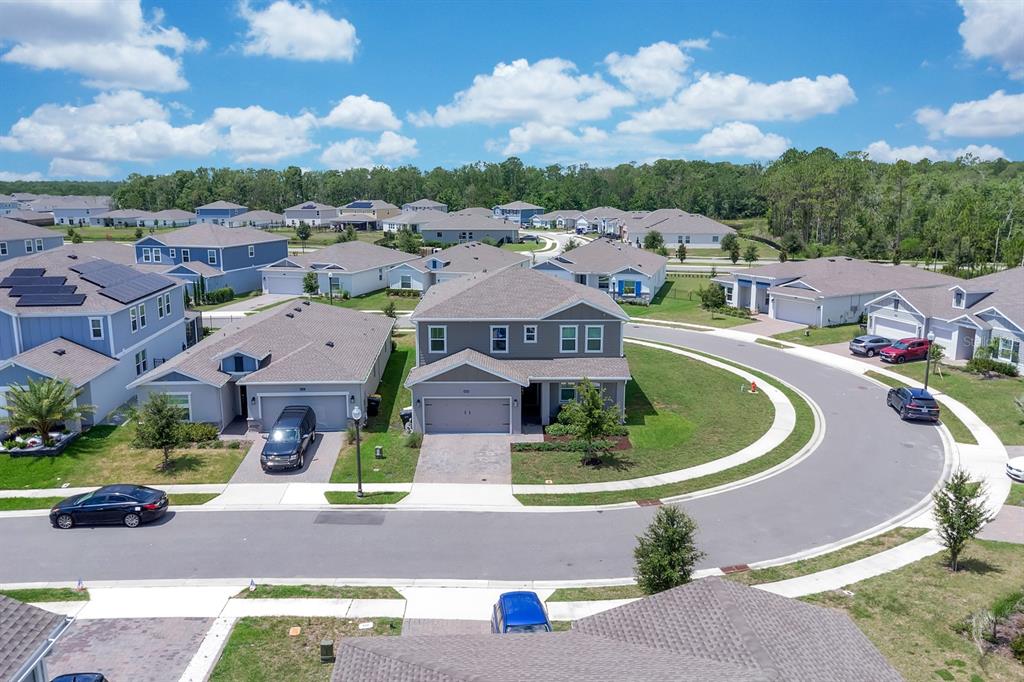An aerial view shows a suburban neighborhood with single-family homes and a curved street — 4064 REDBRIDGE LOOP, DAVENPORT, FL
