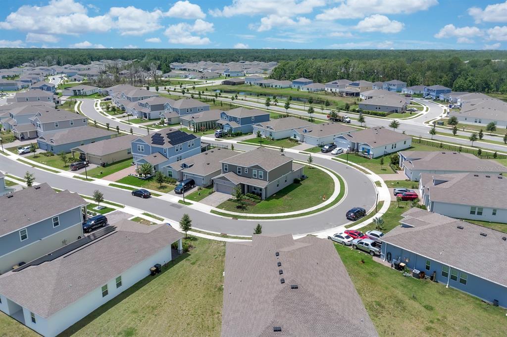 An aerial view shows a suburban neighborhood with houses, paved streets, and green lawns — 4064 REDBRIDGE LOOP, DAVENPORT, FL