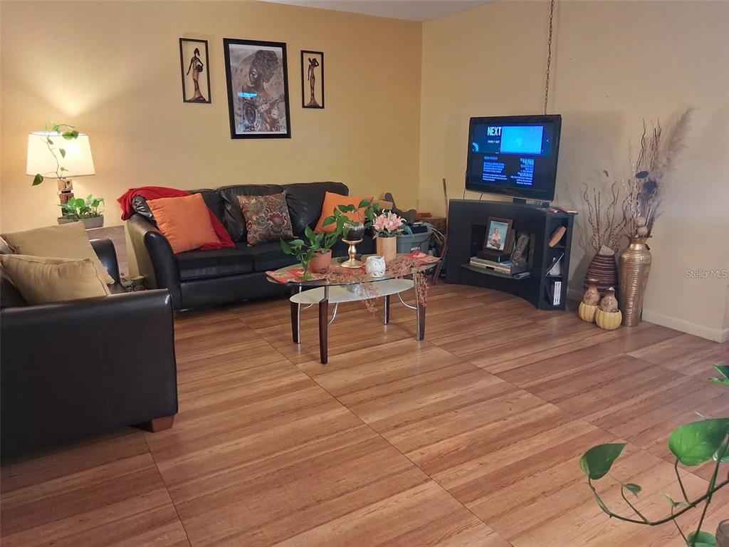 A living room features a black leather sofa, a glass coffee table, and wood-look flooring — 576 BAHIA UNIT A, OCALA, FL
