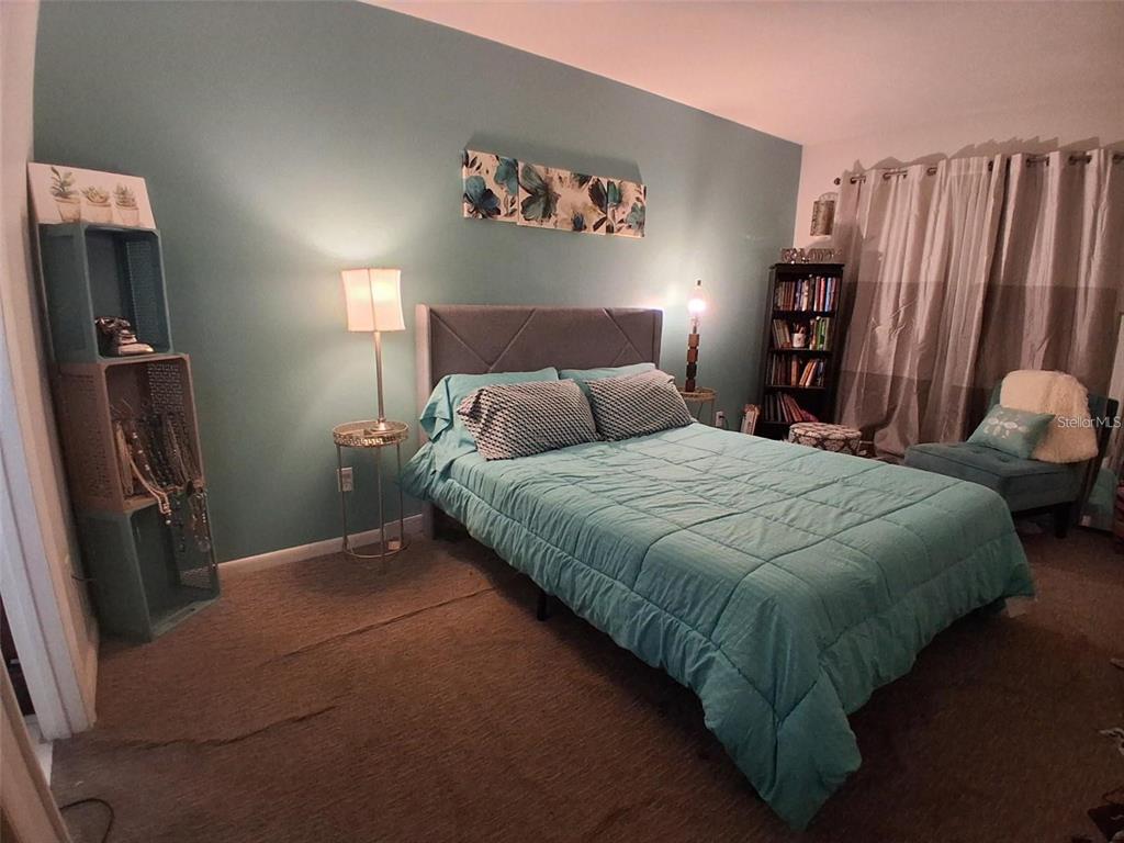 A bedroom features a teal accent wall, a grey upholstered bed, and a bookshelf — 576 BAHIA UNIT A, OCALA, FL