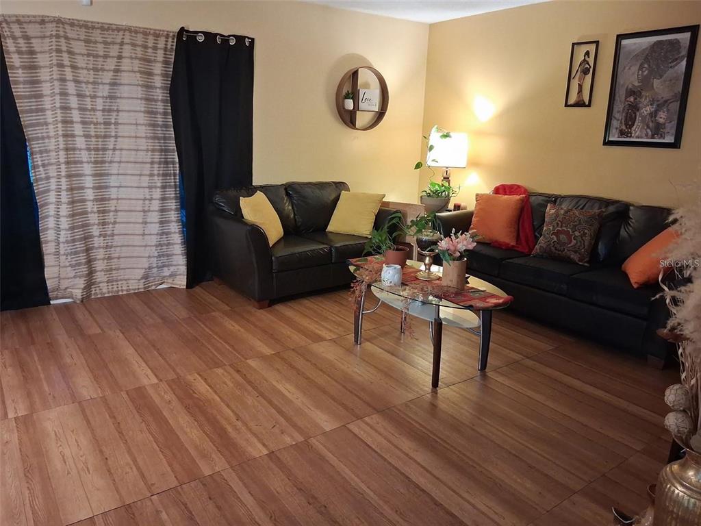 A living room features wood-look flooring, two black leather sofas, and a glass coffee table — 576 BAHIA UNIT A, OCALA, FL