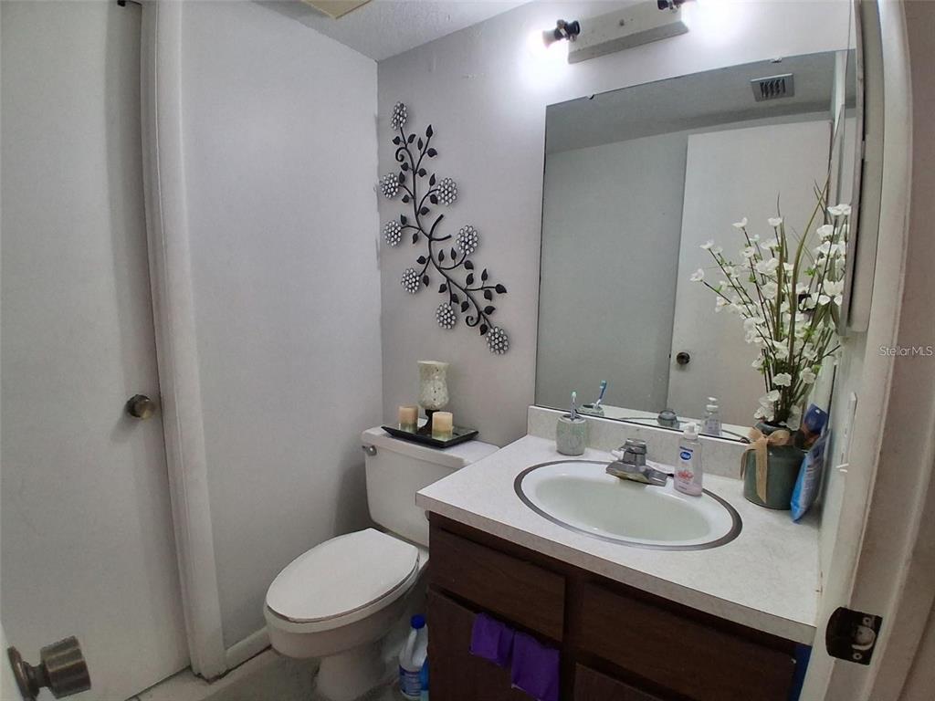 A bathroom features a vanity with a white countertop, a toilet, and wall-mounted floral decor — 576 BAHIA UNIT A, OCALA, FL