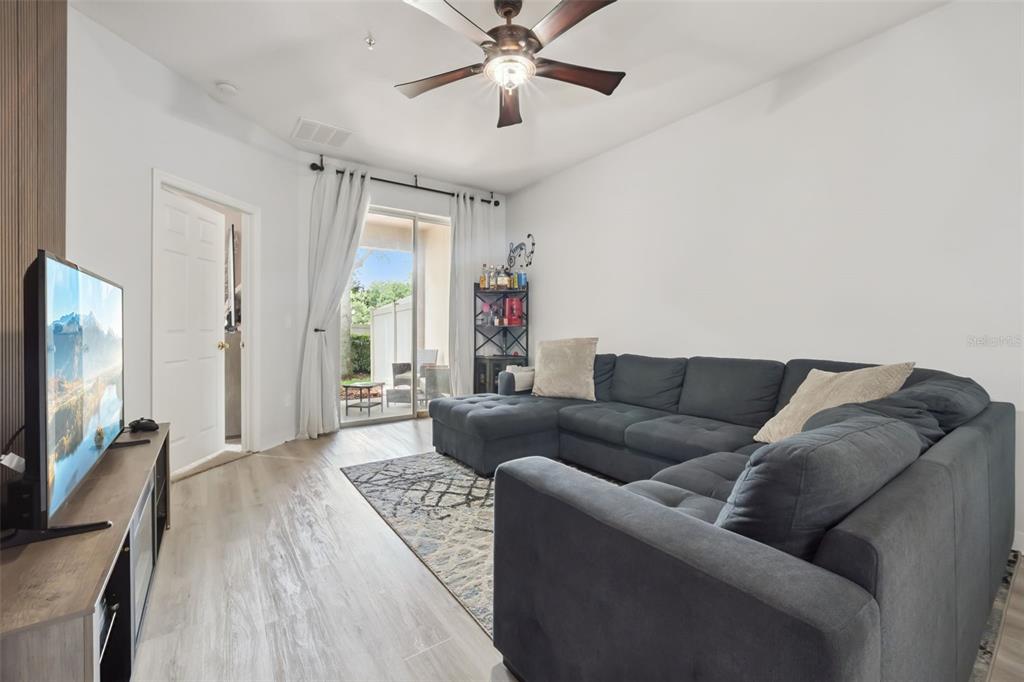 A living room features a gray sectional sofa, a television, and a sliding glass door — 1320 GLENLEIGH DRIVE, OCOEE, FL