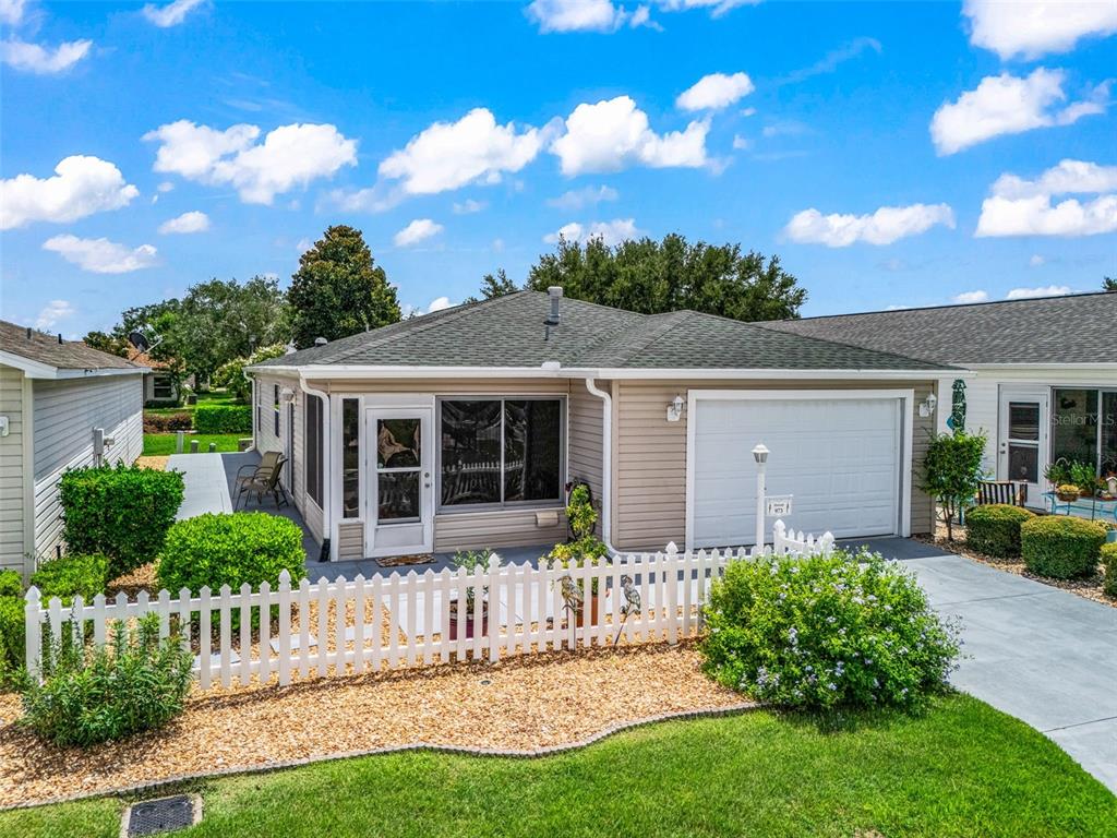 A single-story house with beige siding, a white garage door, and a white picket fence — 973 YORK TERRACE, THE VILLAGES, FL