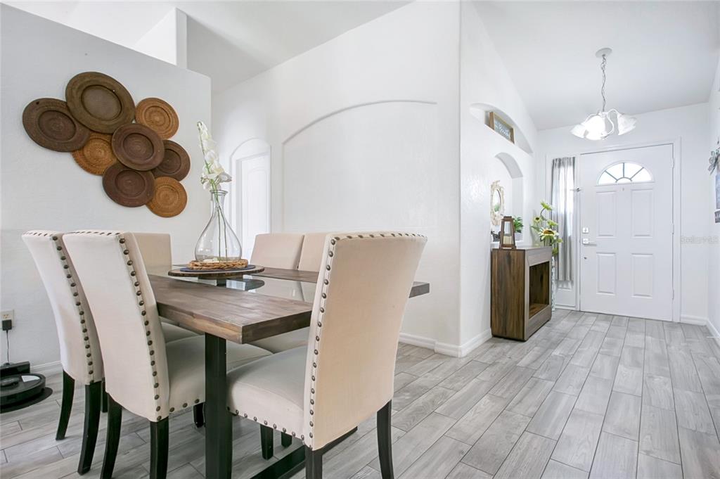 A dining area features a wooden table, upholstered chairs, and wall-mounted woven decorative plates — 4202 CRACKER COURT, ST CLOUD, FL