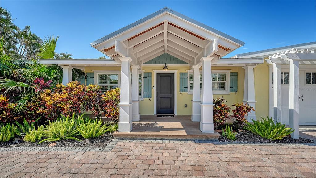 A single-story house with a paved driveway, white garage doors, and a covered entryway — 602 BUTTONWOOD DRIVE, LONGBOAT KEY, FL