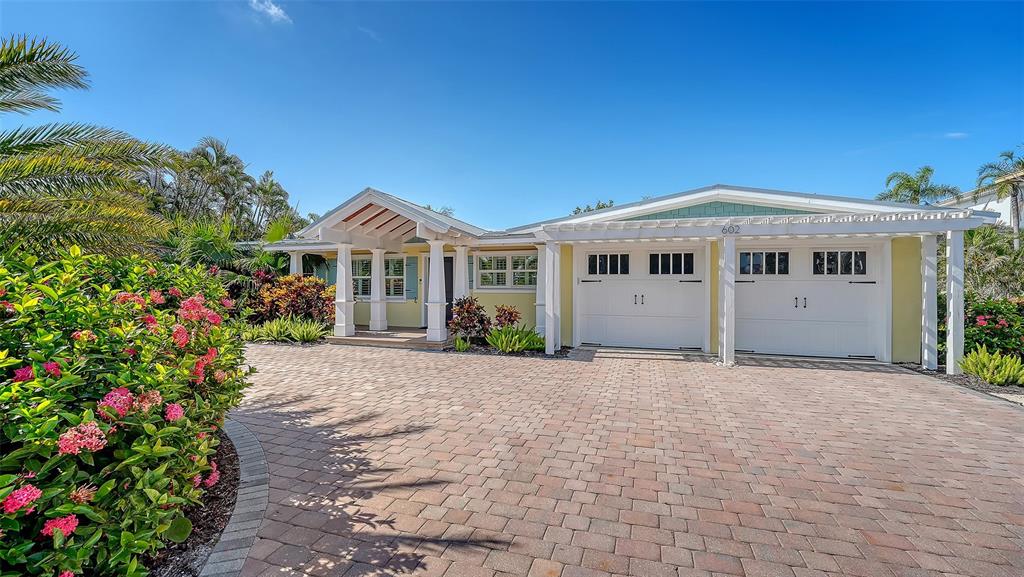 A single-story house with a paved driveway, a two-car garage, and lush tropical landscaping — 602 BUTTONWOOD DRIVE, LONGBOAT KEY, FL