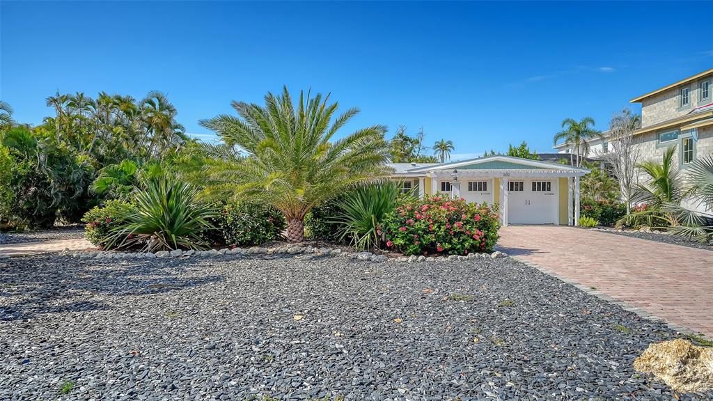 A brick paver path leads toward a house surrounded by tropical landscaping and palm trees — 602 BUTTONWOOD DRIVE, LONGBOAT KEY, FL