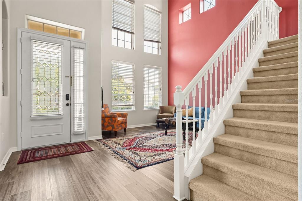 A staircase with white railings sits beside a hallway and a red-walled bar area — 1699 SWALLOWTAIL LANE, SANFORD, FL