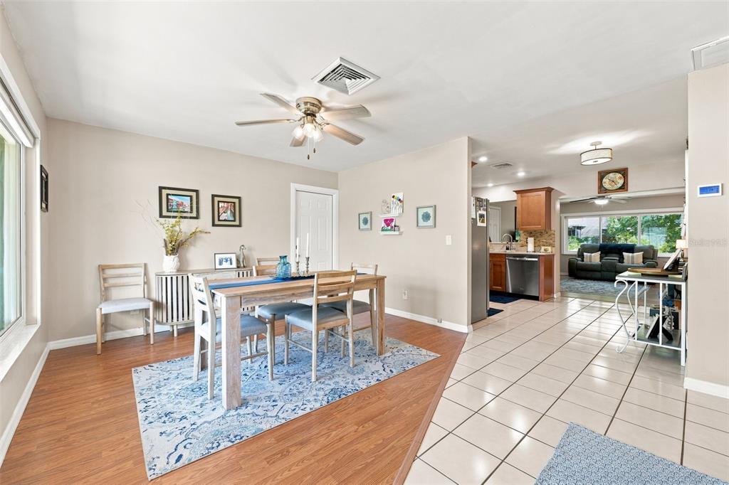 A dining area with wood-look flooring transitions into a tiled kitchen and living space — 8037 POWDER HORN CIRCLE, LARGO, FL