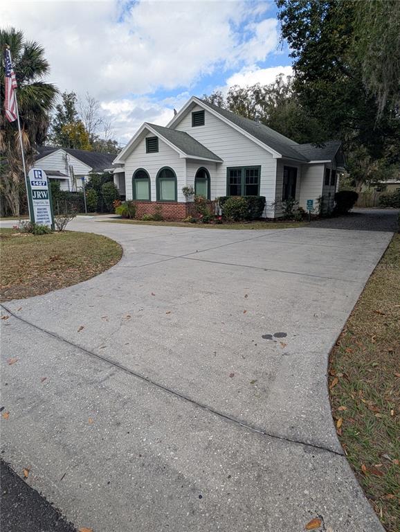 A white house with a concrete driveway and a sign stands under a cloudy sky — 1427 E FORT KING STREET, OCALA, FL