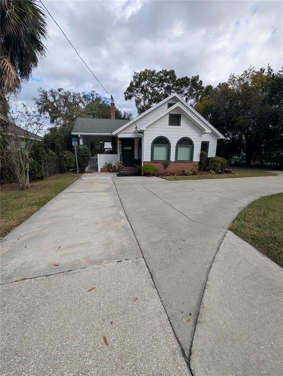 A white house with a brick base and a concrete driveway under a cloudy sky — 1427 E FORT KING STREET, OCALA, FL