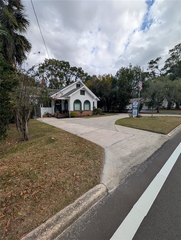 A white house with arched windows and a large concrete driveway sits on a lawn — 1427 E FORT KING STREET, OCALA, FL
