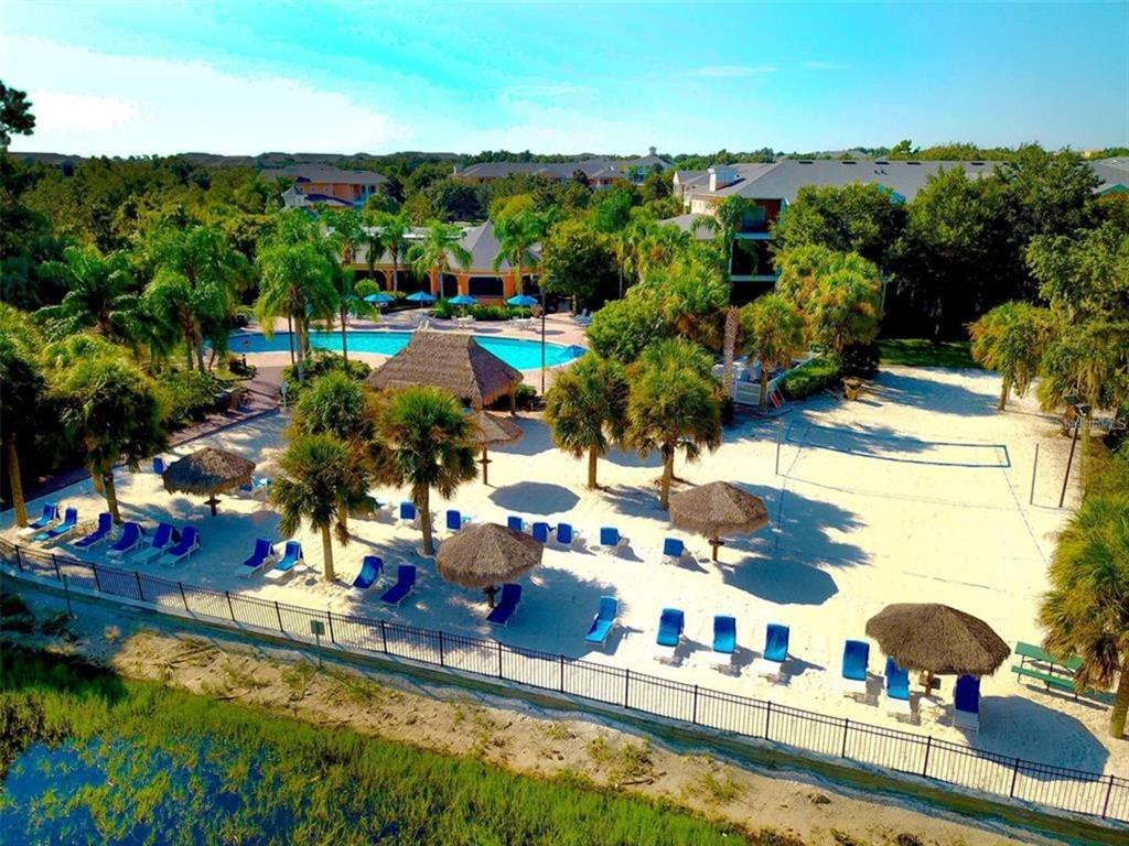 An aerial view shows a sandy beach area with lounge chairs, umbrellas, and a pool — 614 RUM RUN, DAVENPORT, FL