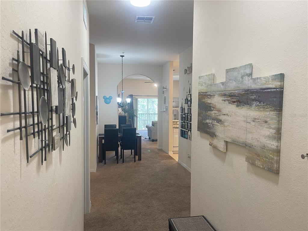 A hallway with wall art leads to a dining area and a living room beyond — 614 RUM RUN, DAVENPORT, FL