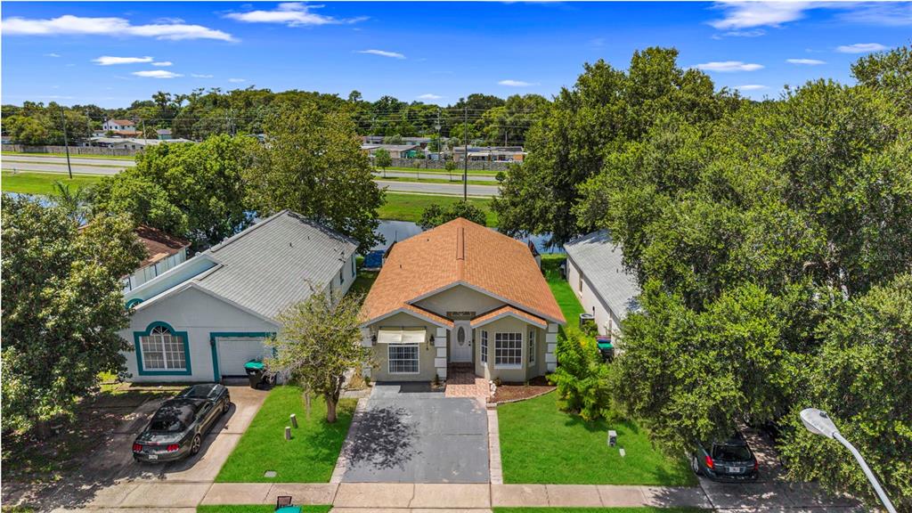 An aerial view shows three single-story houses with driveways and lawns near a road and canal — 1218 SHOSHANNA DRIVE, ORLANDO, FL