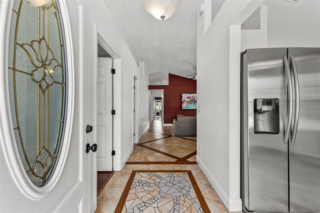 A hallway with tiled floors leads past a stainless steel refrigerator toward a red-walled room — 1218 SHOSHANNA DRIVE, ORLANDO, FL