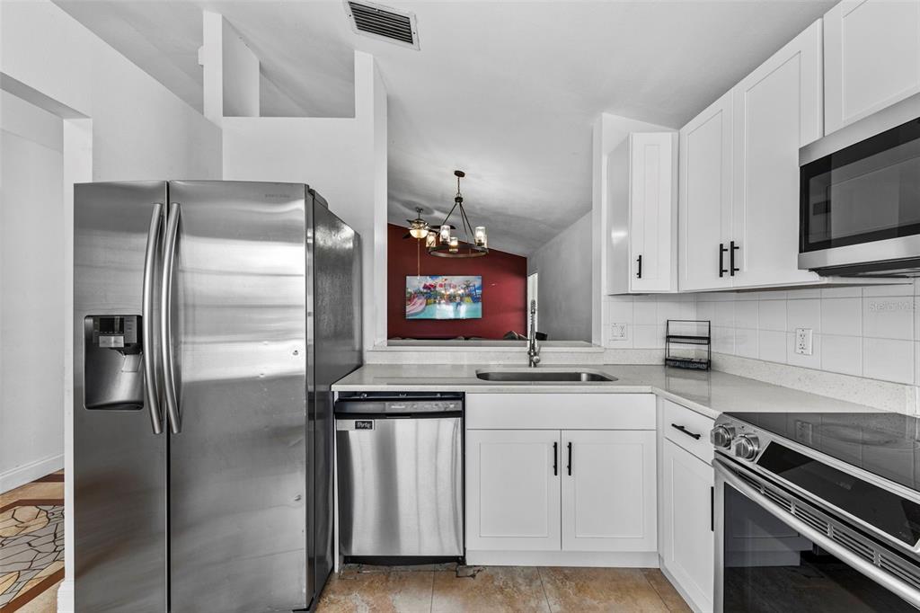 A kitchen with white cabinets, stainless steel appliances, and a pass-through window to another room — 1218 SHOSHANNA DRIVE, ORLANDO, FL