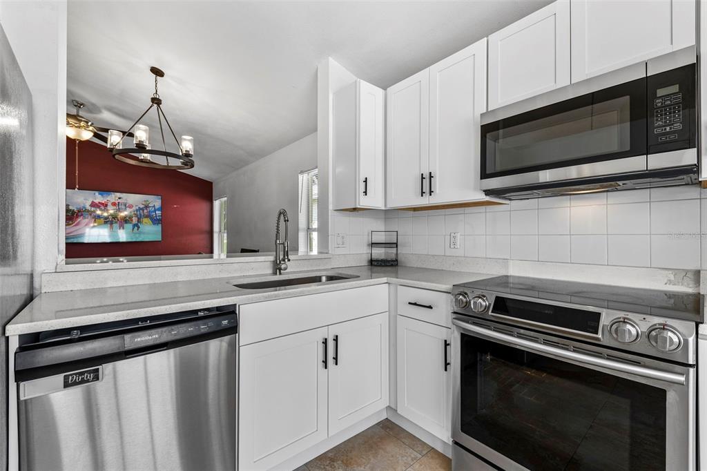 A kitchen with white cabinets, stainless steel appliances, and a view into an adjacent room — 1218 SHOSHANNA DRIVE, ORLANDO, FL