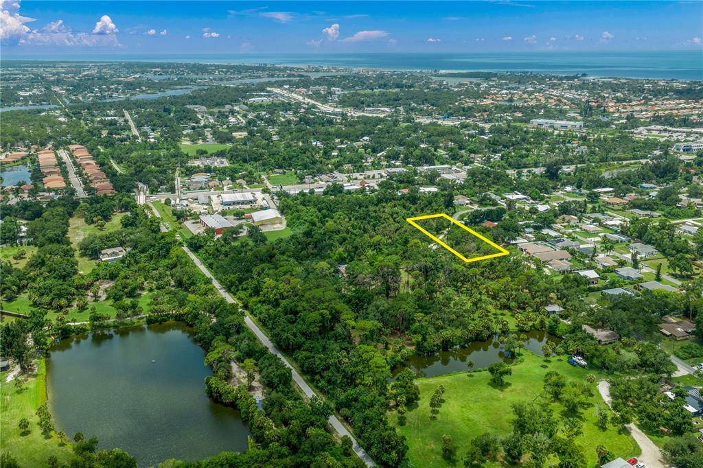 An aerial view shows a wooded lot outlined in yellow surrounded by residential neighborhoods and ponds — 0 TWIN LAKES AVENUE, NOKOMIS, FL