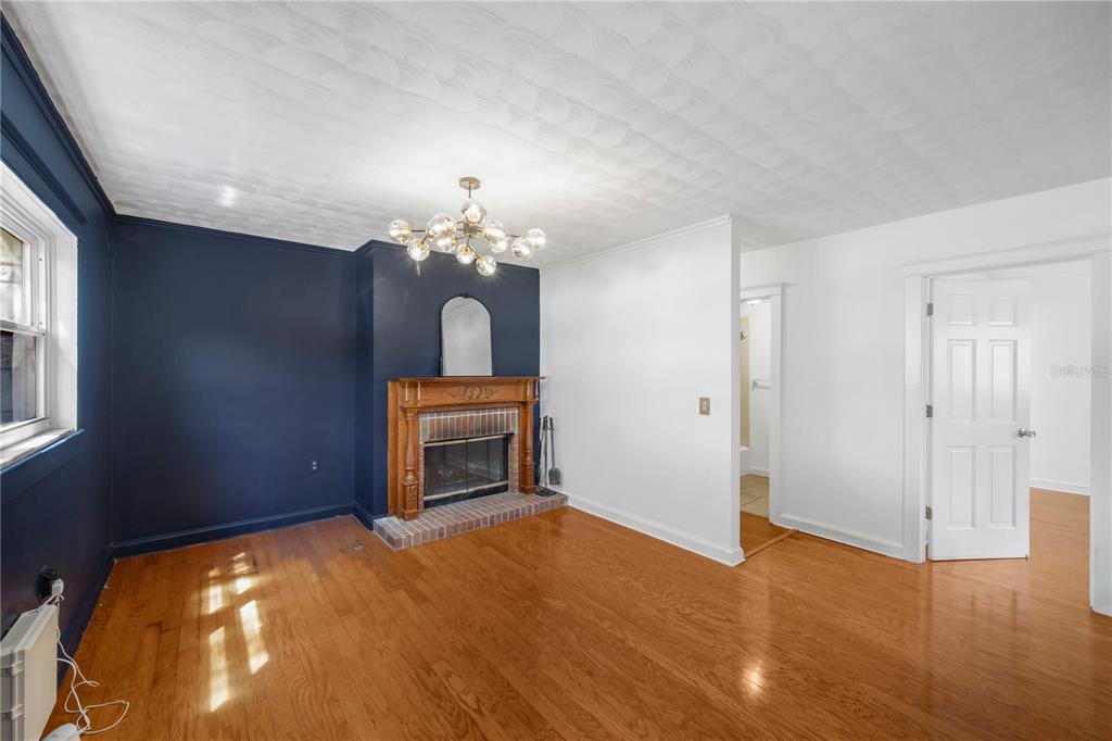 A living room with hardwood floors, a brick fireplace, and a dark blue accent wall — 1708 WOODBINE DRIVE, BRANDON, FL