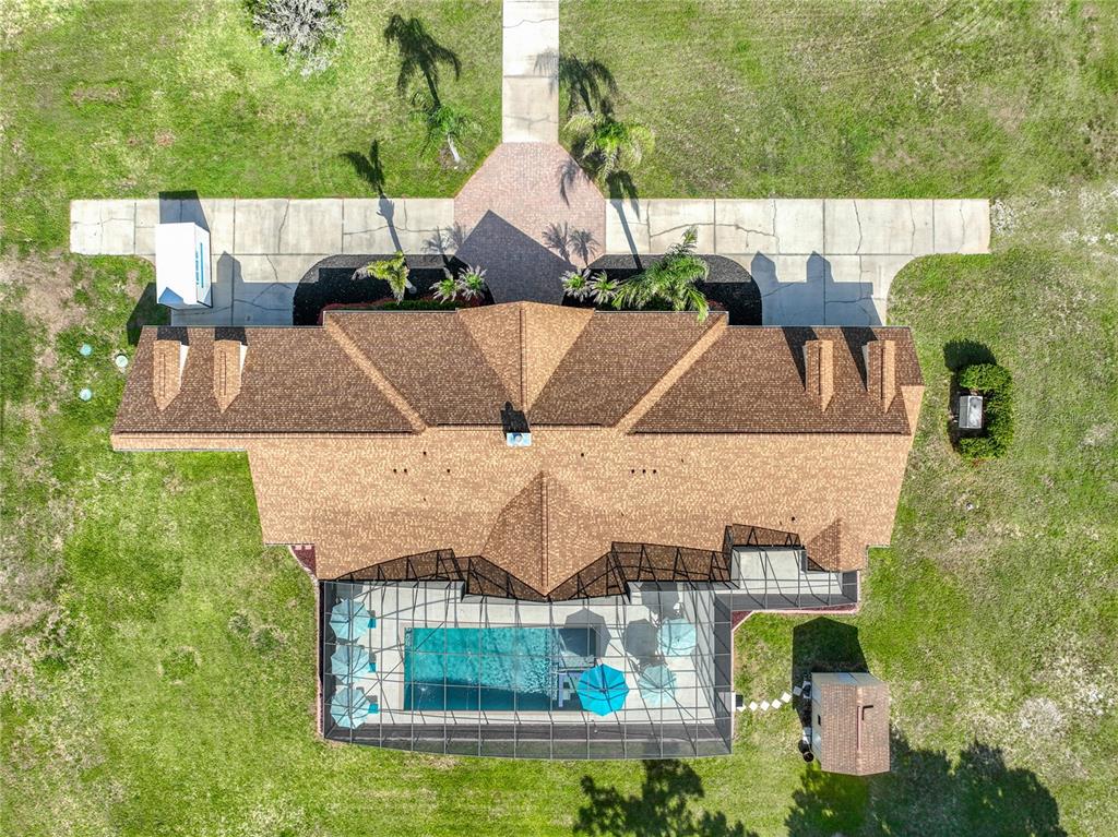 An aerial view shows a house with a pool surrounded by trees and open fields — 2300 PINE MEADOWS PLACE, CHULUOTA, FL