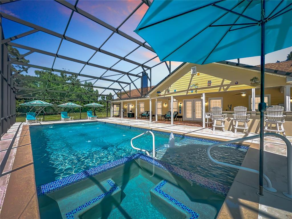 A screened-in pool and hot tub area with patio furniture and a yellow house exterior — 2300 PINE MEADOWS PLACE, CHULUOTA, FL