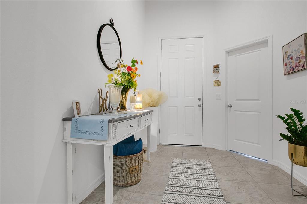 An entryway features a white console table, a round mirror, and tile flooring — 2009 NAPOLI DRIVE, ST CLOUD, FL