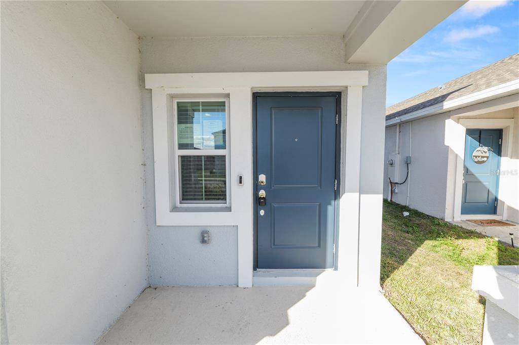 A blue front door and a window are visible on the porch of a house — 1465 DEEPWATER CIRCLE, EAGLE LAKE, FL