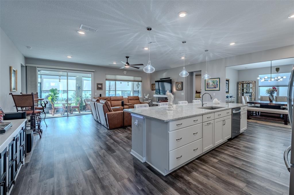 An open-concept kitchen with a large granite island overlooks a living room and dining area — 10586 SW 98TH PLACE, OCALA, FL