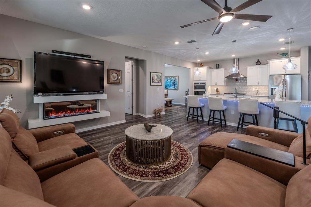 A living room with a fireplace and television opens into a kitchen with a breakfast bar — 10586 SW 98TH PLACE, OCALA, FL