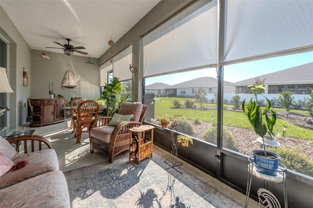 A sunroom with wicker furniture, a ceiling fan, and large screened windows overlooking a backyard — 10586 SW 98TH PLACE, OCALA, FL