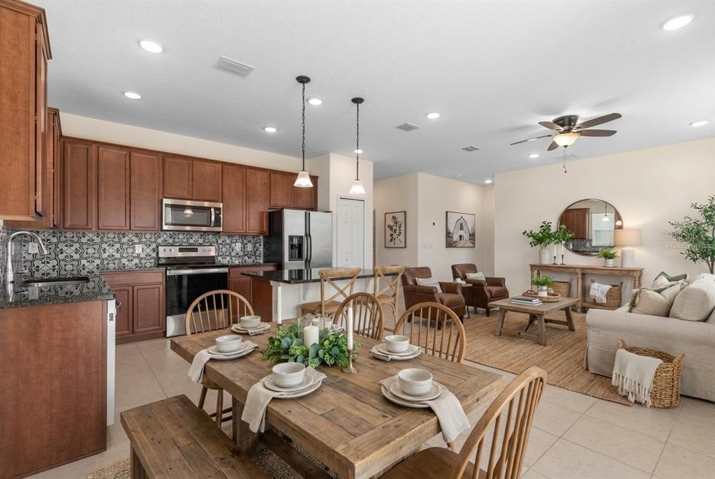 An open-concept kitchen, dining area, and living room featuring wood cabinetry and tile flooring — 3 OAKLEAF WAY, PALM COAST, FL
