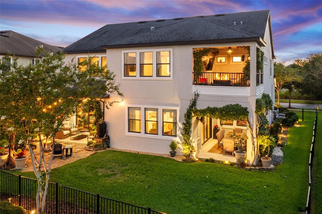 A two-story house exterior features a covered patio, a second-story balcony, and a fenced yard — 2998 RIDERS PASS, ODESSA, FL