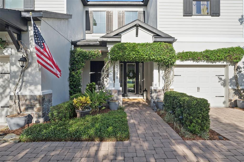 The exterior of a two-story home features a brick walkway, stone accents, and climbing vines — 2998 RIDERS PASS, ODESSA, FL