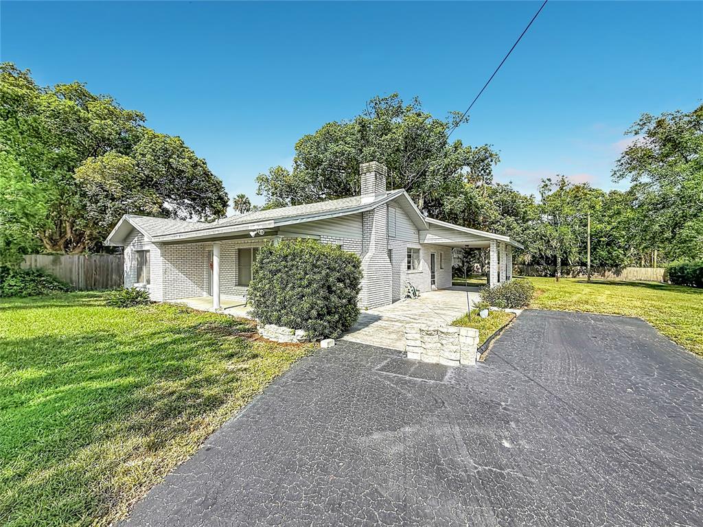 A single-story white brick house features a covered porch, a chimney, and an asphalt driveway — 3271 ROBINSON STREET, ZELLWOOD, FL