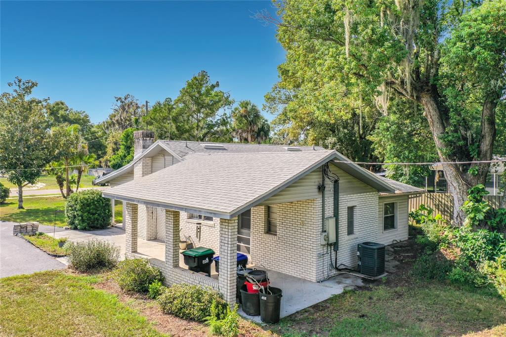 An exterior view of a single-story brick house with a covered porch and shingled roof — 3271 ROBINSON STREET, ZELLWOOD, FL