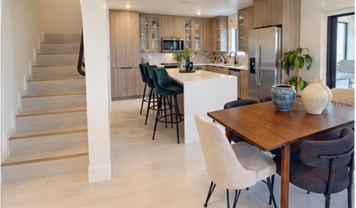 A modern kitchen with light wood cabinets, a white island, and an adjacent dining area — 6471 CHORUS DRIVE, MASCOTTE, FL