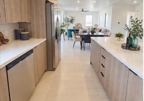 A modern kitchen with light wood cabinets, stainless steel appliances, and a white quartz island — 6471 CHORUS DRIVE, MASCOTTE, FL