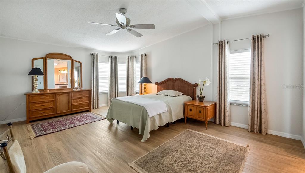 A bedroom features light wood flooring, a bed with a wicker headboard, and a dresser — 3109 MANATEE ROAD, TAVARES, FL