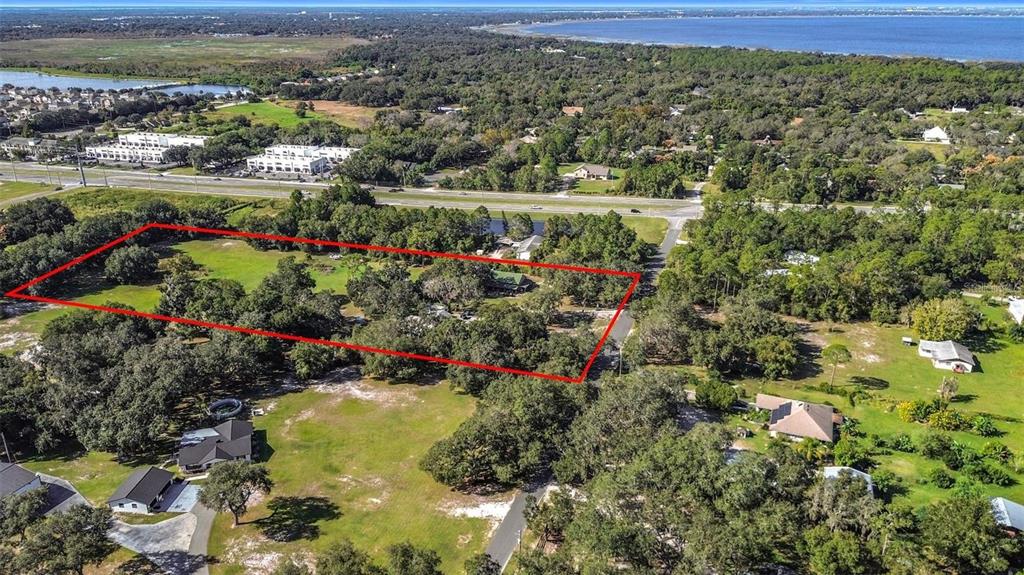 An aerial view shows a rectangular property outlined in red amidst trees and grassy land — 4980 DISSTON DRIVE, ST CLOUD, FL