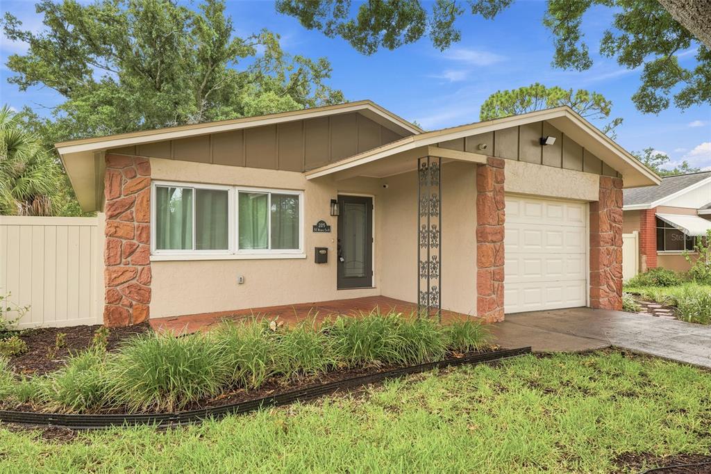 A living room features a grey sectional sofa, hardwood floors, and a large window — 205 SE MONROE CIRCLE N, ST PETERSBURG, FL
