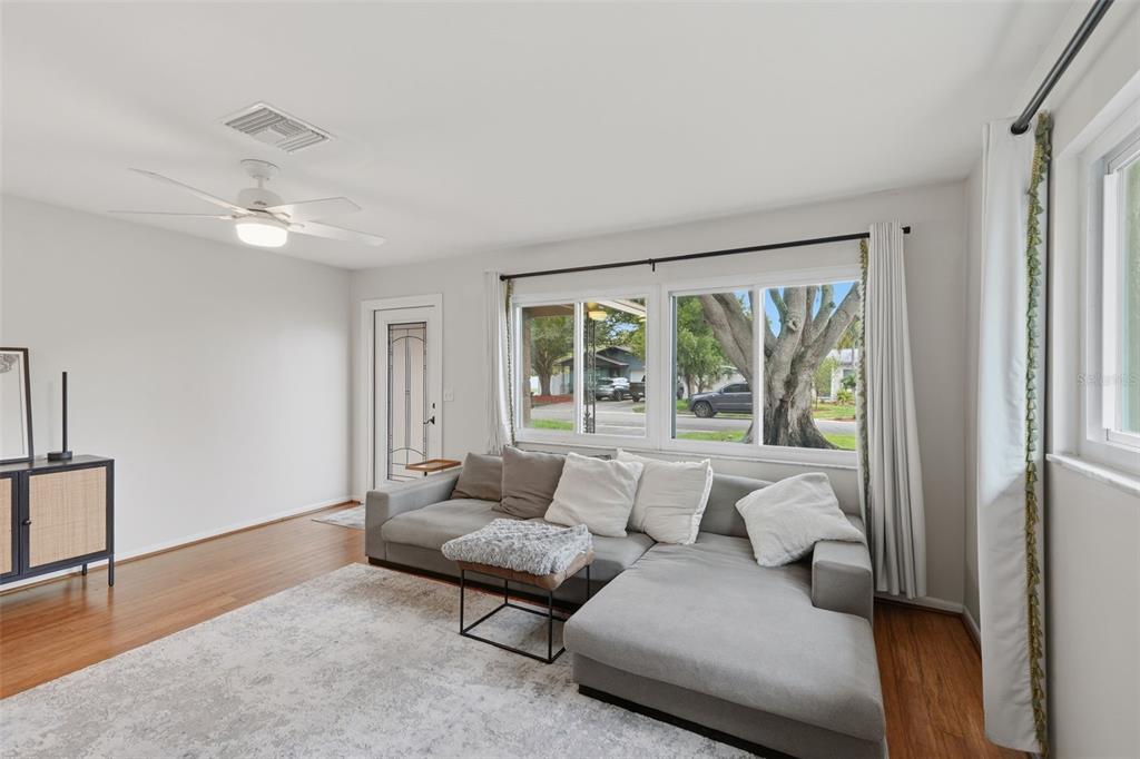 A living room features hardwood floors, a gray sectional sofa, and a black console table — 205 SE MONROE CIRCLE N, ST PETERSBURG, FL