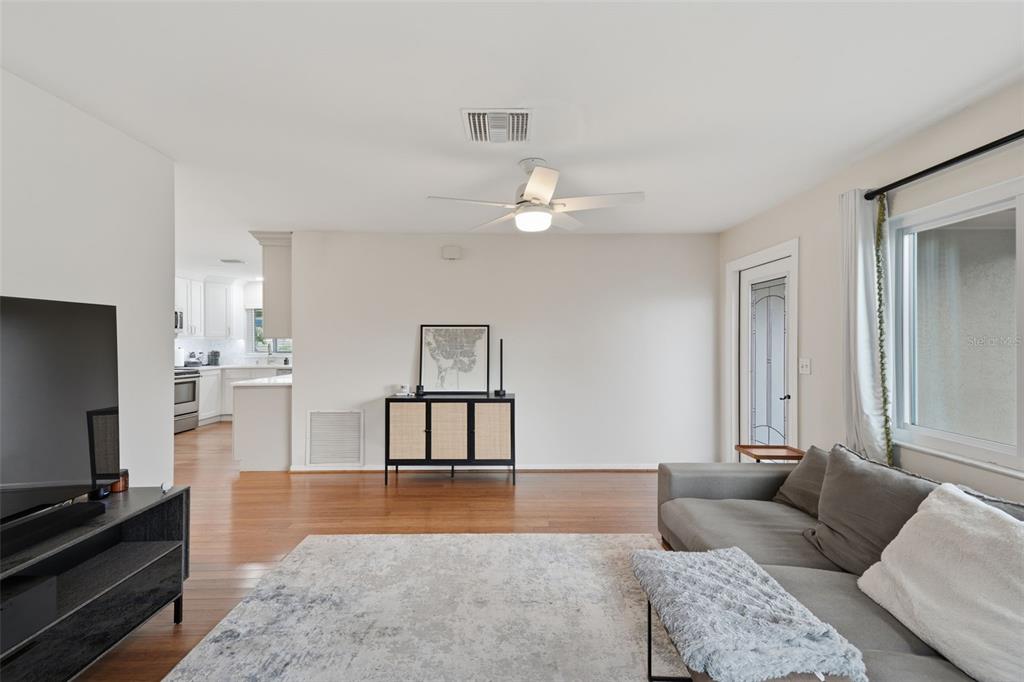 A living room features a ceiling fan, a television on a stand, and hardwood floors — 205 SE MONROE CIRCLE N, ST PETERSBURG, FL
