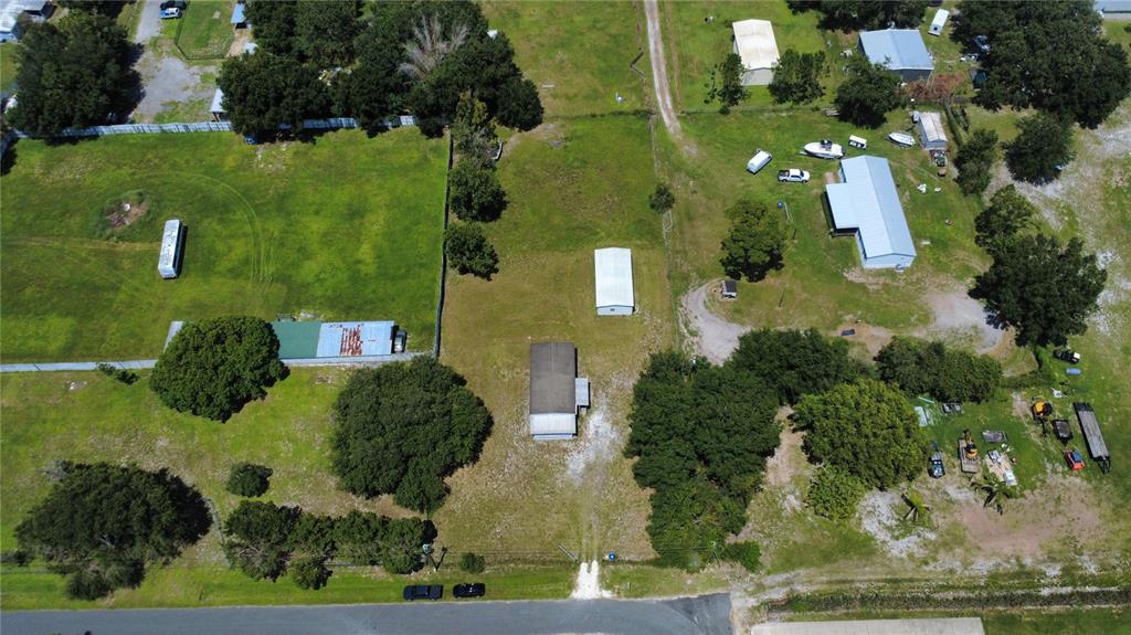 An aerial view shows a rural property with multiple outbuildings, trees, and a gravel driveway — 4641 A STREET, ST CLOUD, FL