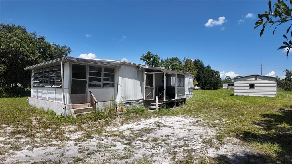 A single-story mobile home with a screened porch and a detached shed on a grassy lot — 4641 A STREET, ST CLOUD, FL